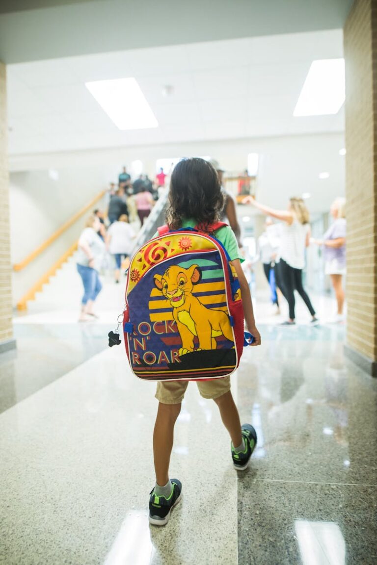 Unrecognizable child with backpack walking in crowded hall